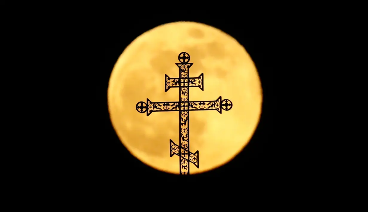 Fenomena super snow moon terlihat di belakang menara salib gereja ortodoks di Minsk, Belarus, Selasa (19/2). Super snow moon terjadi karena orbit bulan berada di posisi paling dekat dengan Bumi. (AP Photo/Grits Sergei)