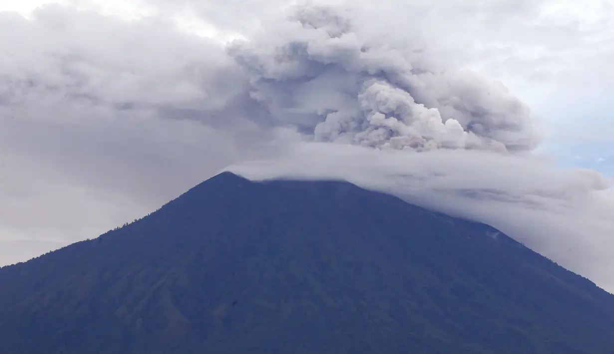 Gunung Agung yang mengeluarkan asap dan abu vulkanis terlihat dari Karangasem, Bali, Rabu (29/11). Gunung Agung masih menghembuskan asap tebal berwarna abu-abu yang mengarah ke selatan-barat daya karena hembusan angin. (AP/Firdia Lisnawati)