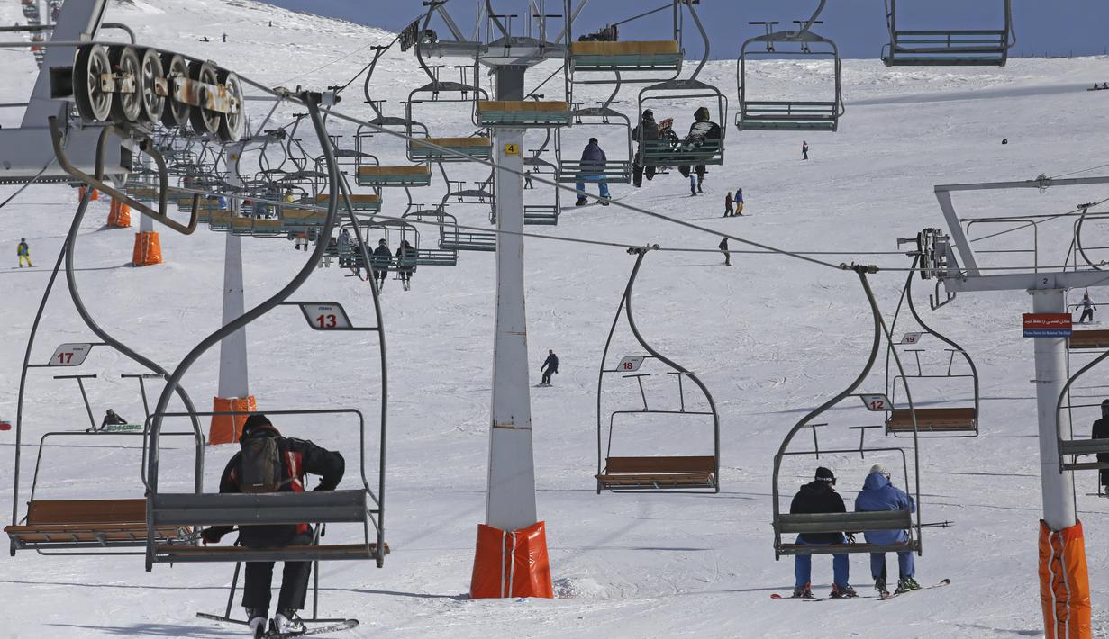 Pemain ski menggunakan kursi gantung di resor ski Tochal di luar ibu kota Teheran, Iran (1/1/2022). Di tengah polusi udara dan kesengsaraan ekonomi, penduduk Teheran menemukan kenyamanan di resor ski di utara Teheran di pegunungan Alborz. (AP Photo/Vahid Salemi)