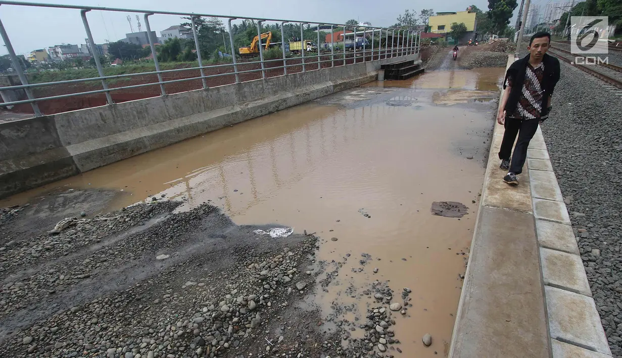 Warga melintasi genangan air di kawasan Kemiri Muka, Depok, Jawa Barat, Senin (2/10). Buruknya sistem drainase menyebabkan air selalu menggenang setiap musim hujan sehingga mengganggu aktivitas warga. (Liputan6.com/Immanuel Antonius)