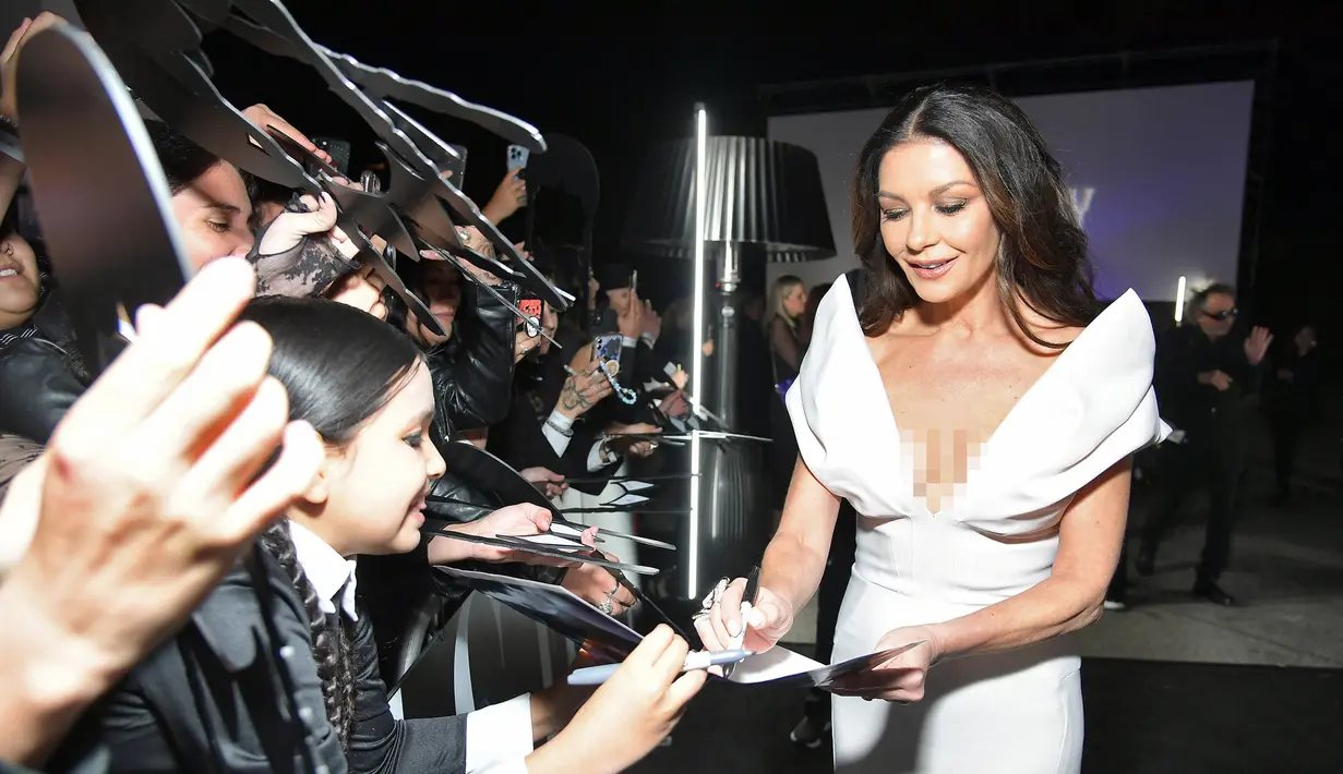 Catherine Zeta-Jones memberikan tanda tangan kepada pengemar saat menghadiri pemutaran perdana film Netfilx "Wednesday" di Los Angeles, California pada 16 November 2022. Aktris berusia 53 tahun itu memamerkan tubuhnya yang ramping dalam balutan gaun ivory yang pas dengan keliman fishtail. (Charley Gallay/Getty Images for Netflix/AFP)