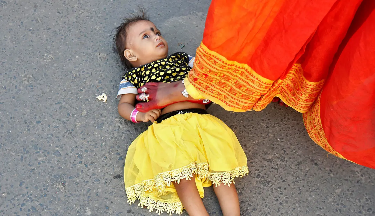 Seorang wanita menginjak anaknya untuk mencari berkah dari Dewa Matahari selama mengikuti festival keagamaan Chhat Puja di Kolkata, India (6/11). (Reuters/Rupak De Chowdhuri)