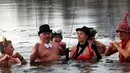 Sejumlah anggota klub renang es "Berliner Seehunde" berendam sambil bermain kembang api di danau Orankesee, Berlin, Jerman (1/1). (REUTERS/Fabrizio Bensch)