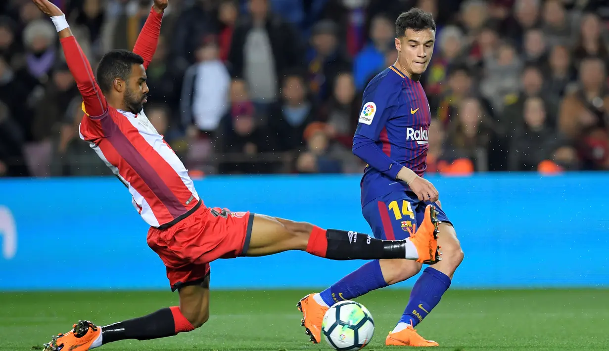 Aksi pemain Girona, Jonas Ramalho (kiri) menghalau bola sepakan pemain Barcelona, Philippe Coutinho pada La Liga Santander di Camp Nou stadium, Barcelona, (24/2/2018). Barcelona menang telak 6-1. (AFP/ Lluis Gene)