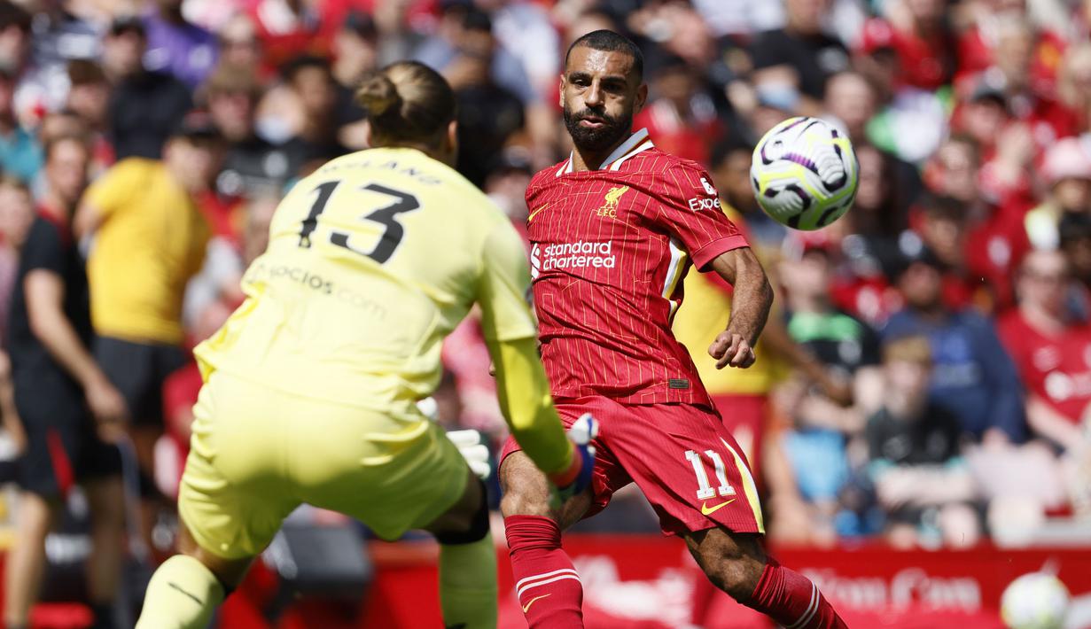 Pemain Liverpool, Mohamed Salah (kanan) berusaha mencetak gol ke gawang Sevilla yang dijaga oleh Orjan Nyland dalam laga persahabatan melawan Sevilla di Anfield, Liverpool, Inggris, Minggu (11/08/2024) WIB. Liverpool menang dengan skor 4-1. (AP Photo/Richard Sellers)