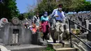 Sebuah keluarga berjalan melewati pemakaman saat Festival Ching Ming atau Hari Sapu Makam di Hong Kong, Selasa (5/4/2022). Ribuan warga Hong Kong memberi hormat kepada leluhur dan kerabat mereka selama festival tahunan ini. (AP Photo/Vincent Yu)