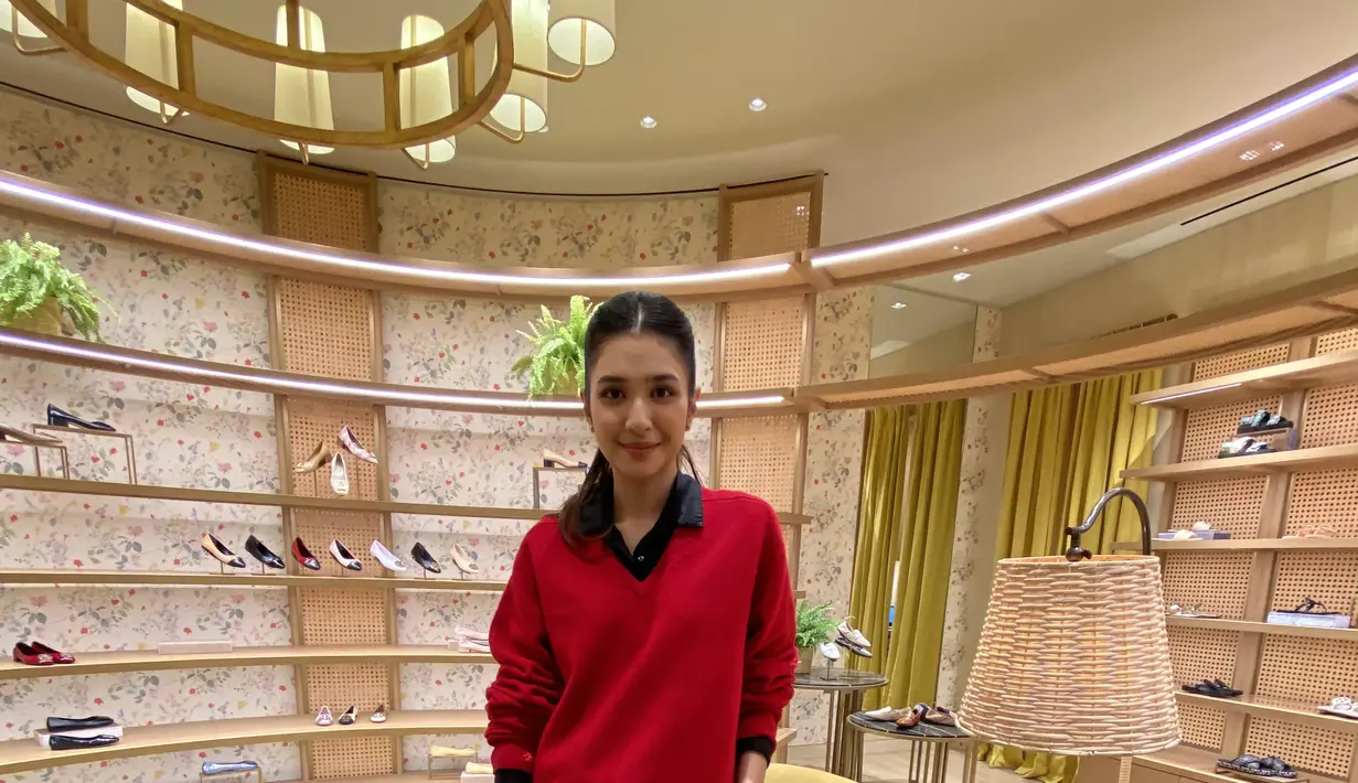 Mikha Tambayong tampil smart casual mengenakan inner kemeja hitam dipadukan v neck sweater merah serta celana coklat.  [Anisha Saktian]
