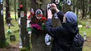 Orang-orang mengunjungi tugu peringatan tempat para korban rezim diktator Soviet Joseph Stalin dimakamkan di hutan di pinggiran Saint Petersburg pada 30 Oktober 2025. Rusia memperingati Hari Korban Represi Politik untuk mengenang ribuan korban yang gugur dalam represi rezim Komunis Soviet. (Olga MALTSEVA/AFP)