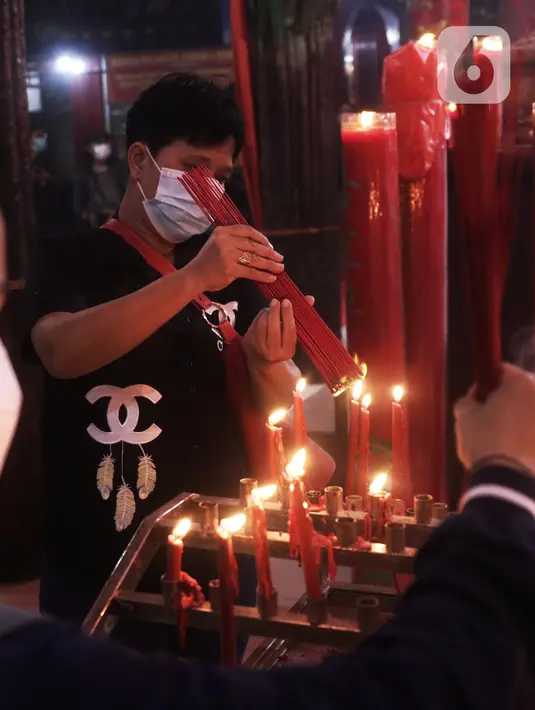 Warga keturunan Tionghoa menyalakan hio untuk sembahyang malam Imlek di Klenteng Boen San Bio Tangerang, Kamis (11/2/2021). Meskipun di tengah pandemi Covid 19, sembahyang Imlek 2572 dilakukan dengan protokol kesehatan yang ketat dan membatasi jumlah warga yang sembahyang (Liputan6.com/Angga Yuniar)