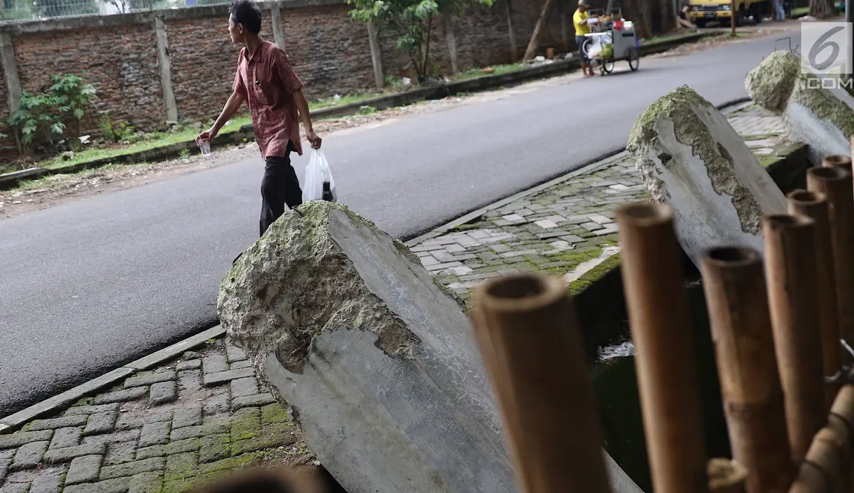 Warga melintas di samping pagar yang ambruk di Taman Hutan Tebet, Jakarta, Kamis (28/3). Kondisi pagar yang ambruk akibat hujan deras tersebut butuh perbaikan karena telah terabaikan selama beberapa bulan terakhir. (Liputan6.com/Immanuel Antonius)