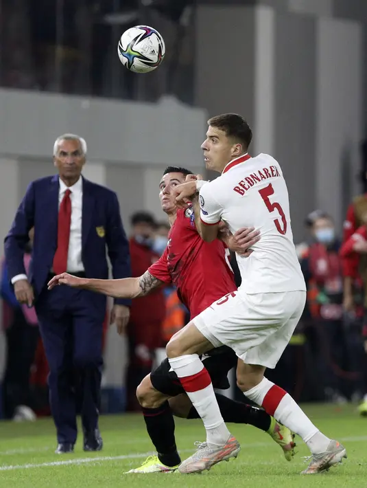 Gelandang Albania Odise Roshi dan bek Polandia Jan Bednarek berebut bola pada lanjutan Grup I Kualifikasi Piala Dunia 2022 Zona Eropa, di Air Albania Stadium, Rabu (13/10/2021) dini hari WIB.  Kemenangan Polandia 1-0 atas Albania diwarnai aksi pelemparan botol oleh suporter. (AP Photo/Franc Zhurda)