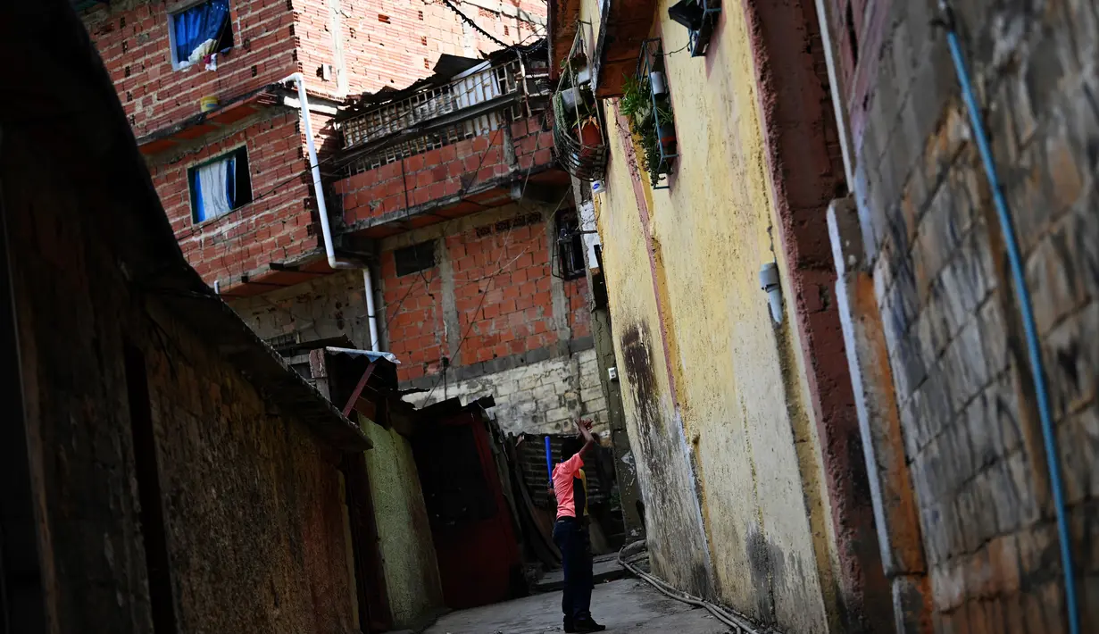 Seorang pria terlihat di antara lorong rumah di permukiman kumuh Petare, Caracas pada 19 Mei 2019. Petare yang merupakan kawasan kumuh terbesar di Venezuela menjadi rumah bagi lebih dari 500.000 jiwa. (Photo by MARVIN RECINOS / AFP)