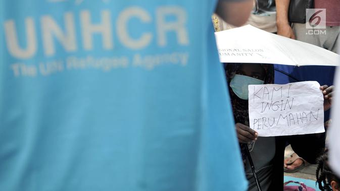 Seorang imigran mengangkat kertas bertuliskan 'Kami Ingin Perumahan' saat bertemu dengan perwakilan UNHCR di trotoar depan Kantor UNHCR Menara Ravindo, Kebon Sirih, Jakarta, Rabu (3/7/2019). (merdeka.com/Iqbal Nugroho)