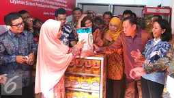 Warga memperlihatkan barang dagangannya kepada sejumlah pejabat negara saat peresmian pilot project penyaluran bantuan sosial melalui Kartu Keluarga Sejahtera (KKS), Jakarta, Kamis (18/08). (Liputan6.com/Angga Yuniar)