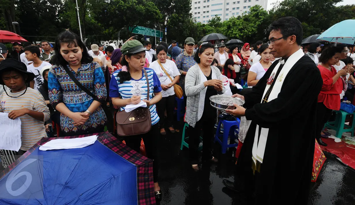 Pastor memimpin jemaat GKI Yasmin Bogor dan HKBP Filadelfia Bekasi melakukan upacara perjamuan saat melakukan misa perayaan Natal 2016 di Silang Barat Laut Monas, Jakarta, Minggu (25/12). (Liputan6.com/Helmi Fithriansyah)