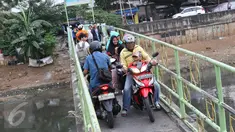 Warga serta pengendara motor menyeberangi Kanal Banjir Barat (KBB) di kawasan Tanah Abang, Jakarta, Jumat (30/12). Tidak tersedianya fasilitas penyeberangan lain membuat warga serta pengendara harus berbagi jalan. (Liputan6.com/Immanuel Antonius)