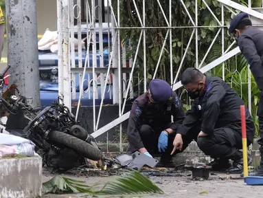 Tim penjinak bom memeriksa puing-puing sepeda motor yang digunakan untuk aksi bom bunuh diri di Gereja Katedral Makassar, Sulawesi Selatan, Senin (29/3/2021). Kepolisian masih melakukan olah TKP serta mengumpulkan serpihan sisa ledakan pada hari kedua pascakejadian. (AP/Masyudi S. Firmansyah)