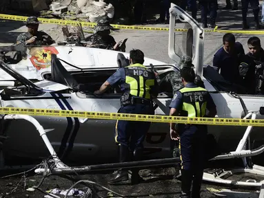 Penyelidik berdiri di dekat puing-puing Helikopter bell 429 yang jatuh di Kota San Pedro, selatan Manila, Kamis (5/3/2020). Helikopter yang membawa Kepala Polisi Filipina Jenderal Archie Francisco Gamboa dan beberapa pejabat PNP lainnya itu jatuh tidak lama setelah lepas landas. (DANTE PERALTA/AFP)