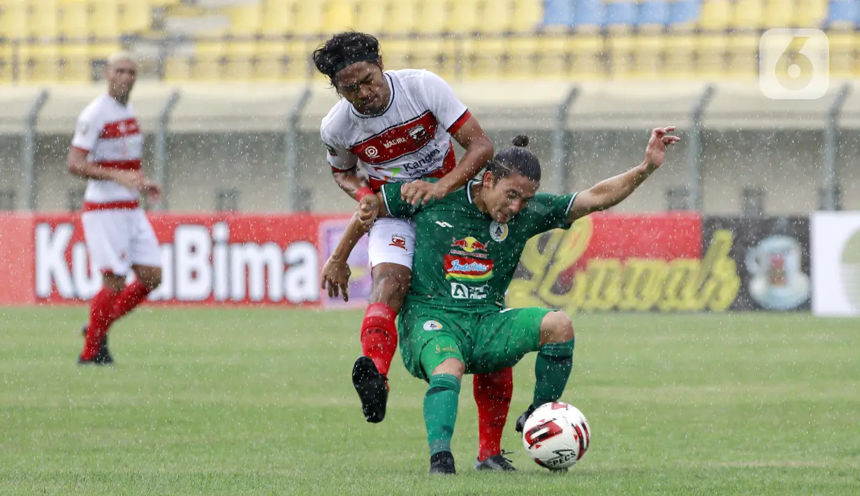 Pemain PSS Sleman Kim Jeffrey Kurniawan berebut bola dengan pemain Madura United Rendika Rama pada laga Piala Menpora 2021 di Stadion Si Jalak Harupat, Bandung, Jawa Barat, Selasa (23/3/2021). Madura United menang 2-1 atas PSS Sleman. (Bola.com/M Iqbal Ichsan)