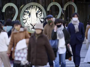 Orang-orang berjalan di sepanjang penyeberangan pejalan kaki di Tokyo (18/1/2022). Pemerintah Jepang sedang mempersiapkan pembatasan sosial di Tokyo dan wilayah lain karena varian omicron dari virus corona menginfeksi lebih banyak orang. (AP Photo/Eugene Hoshiko)
