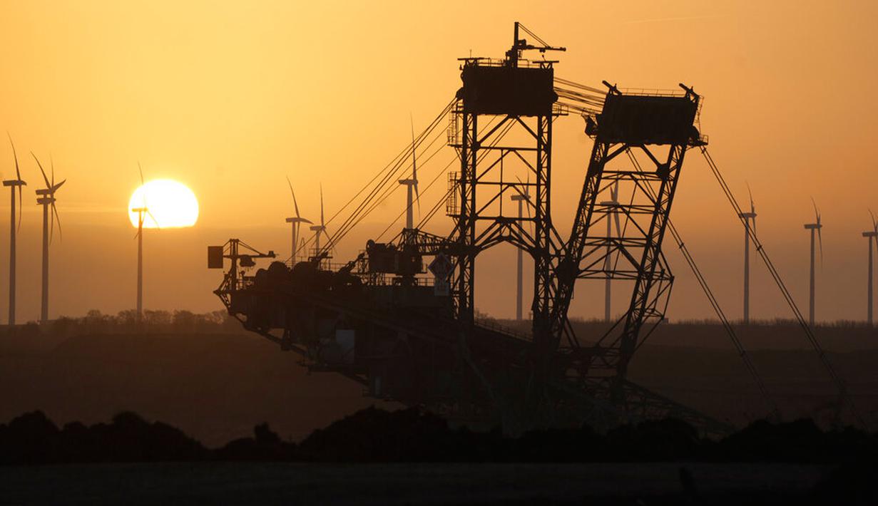 Matahari terbit di belakang ekskavator di tambang batu bara Garzweiler dekat Desa Luetzerath, Erkelenz, Jerman, 10 Januari 2023. Desa Luetzerath harus dibongkar untuk memperluas tambang batu bara di dekat perbatasan Belanda tersebut. (AP Photo/Michael Probst)