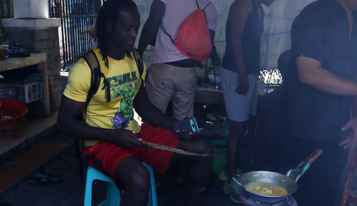 Bek impor Semen Padang, Mahamadou El Hadji tidak ketinggalan mengipas tonseng kambing yang sedang dimasak di Solo, Minggu (13/12/2015). (Nicklas Hanoatubun)