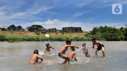 Anak-anak bermain pada aliran Sungai Cisadane di kawasan Keranggan, Setu, Tangerang Selatan, Banten, Minggu (20/3/2022). Cuaca panas terik dimanfaatkan mereka untuk berendam sambil bermain. (merdeka.com/Arie Basuki)