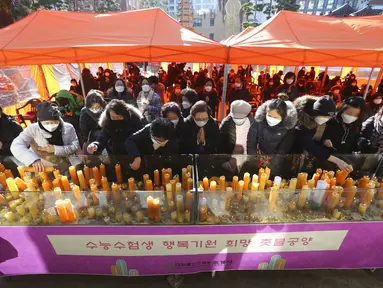 Para orangtua meletakkan lilin selama kebaktian khusus untuk mendoakan keberhasilan anak-anak mereka dalam ujian masuk perguruan tinggi di Kuil Buddha Jogyesa, Seoul, Korea Selatan, Kamis (3/12/2020). Ujian diikuti ratusan ribu siswa, termasuk puluhan siswa pasien COVID-19. (AP Photo/Ahn Young-joon)