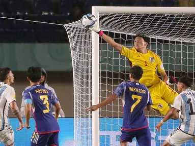 Kiper Timnas Jepang U-17, Wataru Goto (kanan atas) berhasil menghalau bola tendangan dari pemain Timnas Argentina U-17 dalam pertandingan Grup D Piala Dunia U-17 2023 yang berlangsung di Stadion Si Jalak Harupat, Selasa (14/11/2023). (Bola.com/Ikhwan Yanuar)