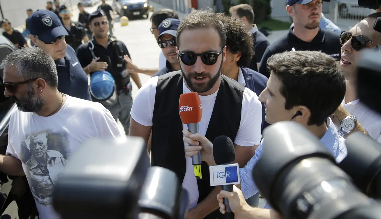 Sejumlah wartawan saat bertanya ke Gonzalo Higuain saat tiba di Juventus Medical Center, Italia (27/7). Mantan striker Napoli ini menjadi pemain kelima yang bergabung dengan Juve pada musim panas ini. (AFP PHOTO/MARCO BERTORELLO)