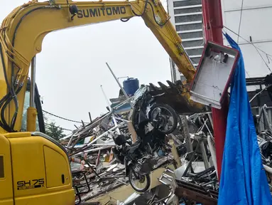 Alat berat mengangkat sebuah motor yang hancur tertimpa puing bangunan PHD, Kota Bekasi, Minggu (23/10). Satu unit eskavator milik Dinas Bina Marga dan Tata Air (Disbimarta) Kota Bekasi dipinjamkan ke lokasi ledakan. (Liputan6.com/Yoppy Renato)