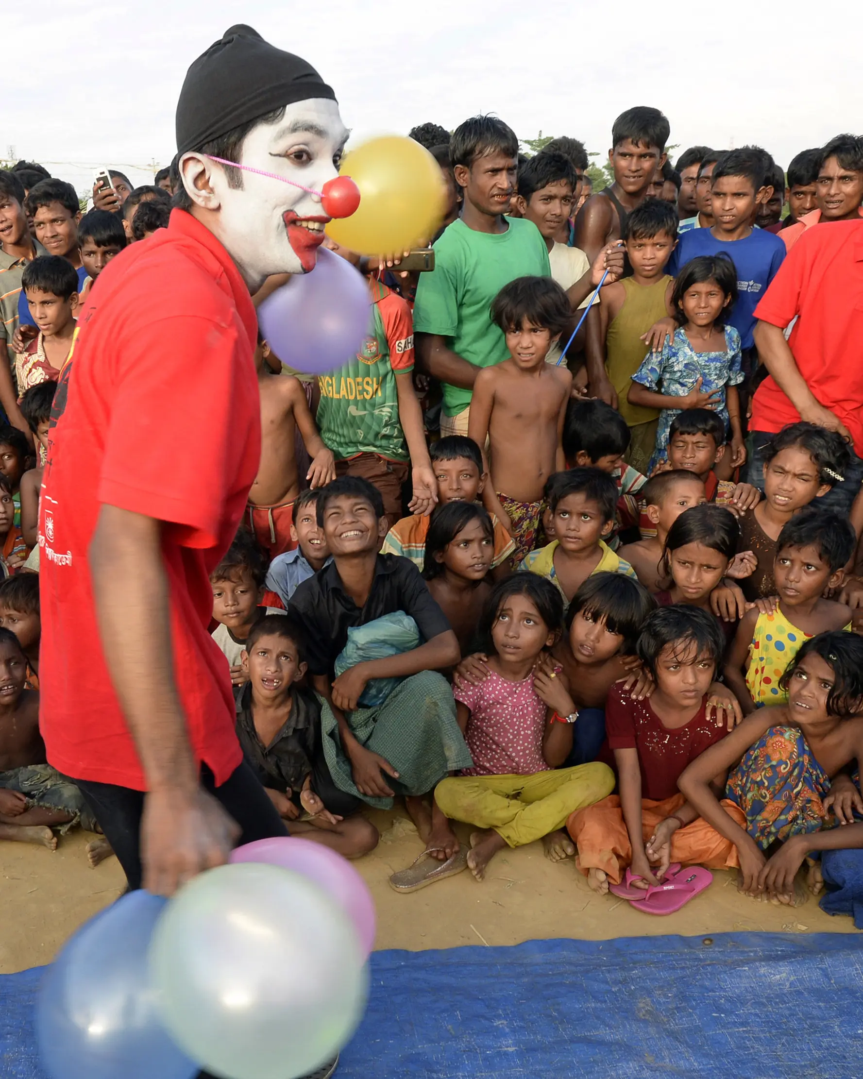 Kelompok teater Drama Therapy mengenakan kostum badut menghibur anak-anak pengungsian Rohingya di kamp pengungsi Kutupalong, Bangladesh (28/10). (AFP Photo/Tauseef Mustafa)