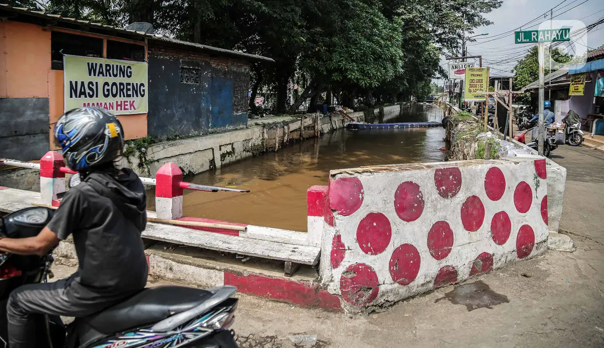 Pengendara motor melintas dekat bantaran Kali Induk Kramat Jati, Jakarta, Rabu(18/5/2022). Pemprov DKI Jakarta melalui Dinas Sumber Daya Air (SDA) berencana akan menormalisasi Kali Induk secara keseluruhan guna mencegah banjir yang melanda kawasan tersebut saat hujan deras mengguyur. (Liputan6.com/FaizaL Fanani)