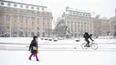 Pengendara sepeda melintasi Lapangan Gustav Adolfs saat salju turun di Stockholm (28/1/2021). Salju diperkirakan terutama menyebabkan masalah di jalan raya, dengan suhu berkisar di sekitar titik beku, yang berarti pengemudi dapat menghadapi es hitam secara tiba-tiba. (Henrik Montgomery/TT via AP)
