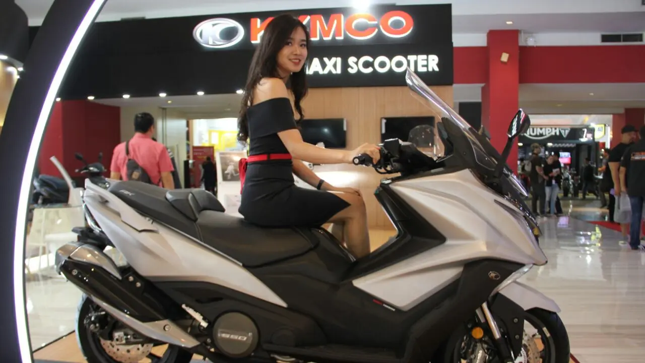 Model seksi berpose di depan Kymco AK550