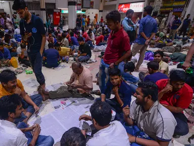 Orang-orang Bangladesh bermain kartu sambil menunggu dalam antrean untuk mendapatkan tiket  mudik lebaran di Stasiun Kereta Kamalapur, Dhaka, Kamis (23/5/2019). Pemudik Bangladesh rela antre berjam-jam dan bahkan menunggu jauh hari sebelum pembukaan loket tiket. (MUNIR UZ ZAMAN/AFP)