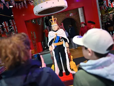 Pembeli mengambil gambar figur LEGO ukuran penuh yang menggambarkan Raja Inggris Charles III di toko mainan Hamleys di pusat kota London pada 27 April 2023. (JUSTIN TALLIS / AFP)