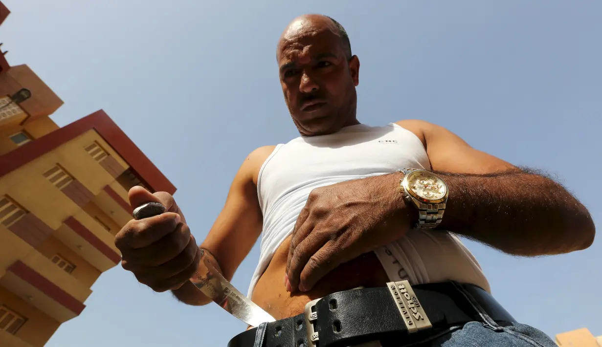 Karim Hussein menusukkan pisau ke perutnya saat unjuk kebolehan di Kairo (18/3/2016). Warga sekitar menjuluki Karim Hussein sebagai "The Pharaoh" karena aksi yang mengerikannya tersebut. (Reuters/ Mohamed Abd El Ghany)