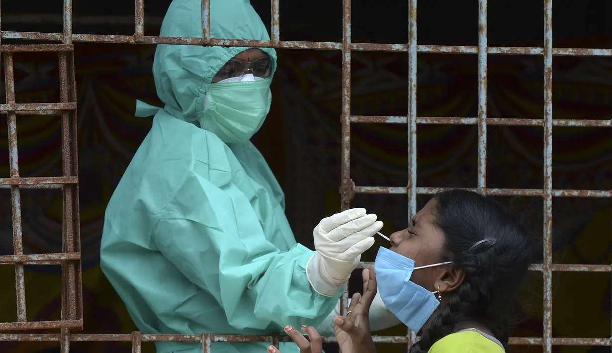Seorang petugas kesehatan mengumpulkan sampel usap dari seorang gadis untuk menguji virus Corona Covid-19 di daerah kumuh di Hyderabad (23/9/2020). (AFP/Noah Seelam)