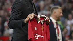 Pemain baru Manchester United Casemiro memegang jerseynya sebelum sesaat sebelum laga MU vs Liverpool dimulai di stadion Old Trafford, di Manchester, Inggris, Senin (22/8/2022). Casemiro yang berpakaian serba hitam, mulai dari jas sampai kemeja yang dikenakannya, berjalan menuju tengah lapangan. (AP Photo/Dave Thompson)