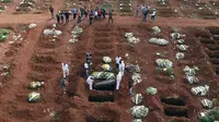 Petugas dengan pakaian pelindung menurunkan peti mati seseorang yang meninggal karena komplikasi COVID-19 ke dalam kuburan di pemakaman Vila Formosa di Sao Paulo, Brasil, Rabu (7/4/2021). Sao Paulo pada Rabu mulai menggali 600 kuburan tambahan setiap hari di pemakaman kotanya (AP Photo/Andre Penner)