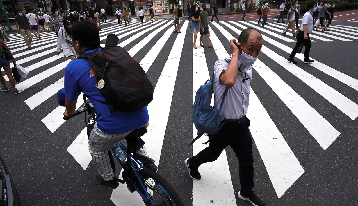 Orang-orang yang memakai masker untuk mencegah penyebaran COVID-19 meyeberang jalan di Shibuya, Tokyo, Jepang, Jumat (3/7/2020). Jepang mengangkat darurat pandemi selama tujuh minggu pada akhir Mei, sebagian besar kegiatan sosial dan bisnis sejak itu telah kembali dimulai. (AP Photo/Eugene Hoshiko)