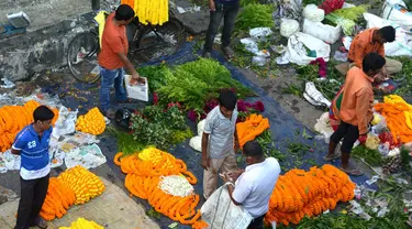 Para pedagang menjajakan bunga untuk dijual selama Festival Durga Puja di pinggir jalan Siliguri, India, Selasa (12/10/2021). Durga Puja juga disebut Durgotsab adalah festival tahunan di Asia Selatan untuk memuja dewi Durga dari agama Hindu. (DIPTENDU DUTTA/AFP)