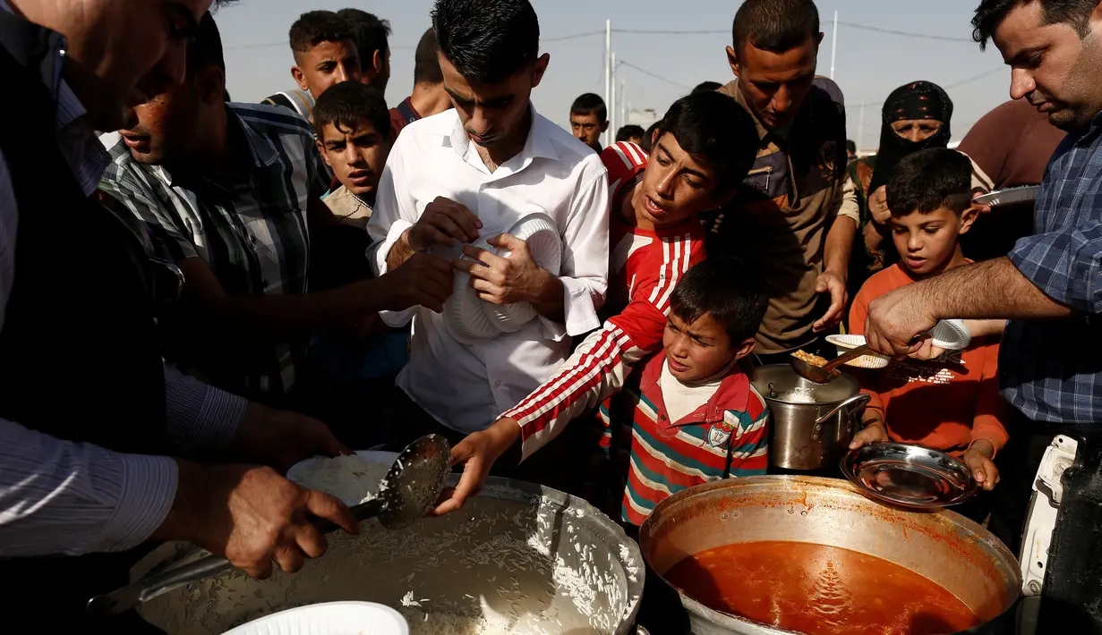 Sejumlah Warga berebut makanan saat mengungsi di kamp Khazer, Irak, (11/11). Warga terpaksa melarikan diri saat Pasukan Irak dan kelompok militan ISIS bentrok memberebutkan kota Mosul. (REUTERS/Zohra Bensemra)