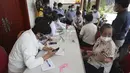 Anggota jurnalis (kanan) berbicara dengan petugas medis sebelum menerima vaksin COVID-19 Sinovac di Phnom Penh, Kamboja, Kamis  (1/4/2021).  Sekitar lima ribu warga Kamboja termasuk jurnalis dan anggota kementerian mulai menerima sebagian dari 1,5 juta dosis vaksin Sinovac. (AP Photo/Heng Sinith)