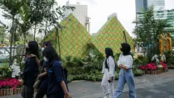 Sejumlah warga berjalan melewati dekorasi bertemakan Idul Fitri di kawasan Bundaran HI, Jakarta, Rabu (27/4/2022). Dekorasi berbentuk masjid, ketupat, dan bedug yang dihiasi oleh tanaman tersebut dalam rangka menyambut Idul Fitri 1443 Hijriah. (Liputan6.com/Faizal Fanani)