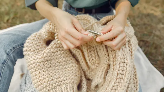 Seorang perempuan sedang melipat sweater rajutnya (Foto Dok: Freepik/prostooleh)