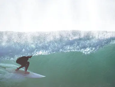 Seorang peselancar mengendarai ombak di Blacks Beach, San Diego, California, Amerika Serikat, 12 Januari 2022. Peselancar di seluruh California Selatan berbondong-bondong ke daerah pantai saat gelombang ombak besar memasuki wilayah tersebut. (AP Photo/Gregory Bull)