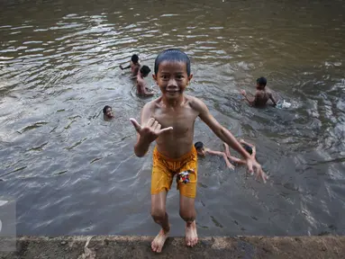 Sejumlah anak mandi di Sungai Ciliwung, Jakarta, Rabu (16/11). Cuaca panas di Jakarta membuat anak-anak tersebut mandi di sungai untuk mendinginkan suhu tubuh. (Liputan6.com/Gempur M Surya)