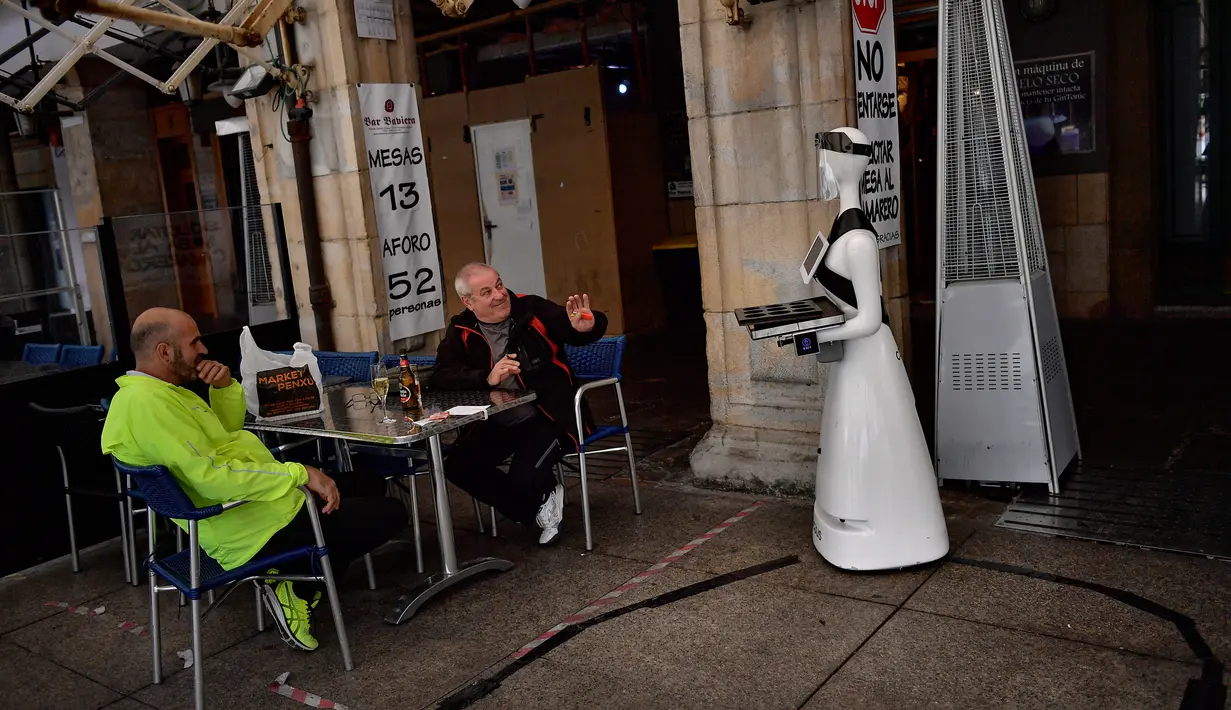 Sebuah robot yang dikenal sebagai "Alexia" mendatangi pelanggan sebuah bar di alun-alun Plaza del Castillo, di Pamplona, Spanyol pada 5 Juni 2020. Robot tersebut digunakan untuk mengurangi penyebaran virus corona Covid-19. (AP Photo/Alvaro Barrientos)